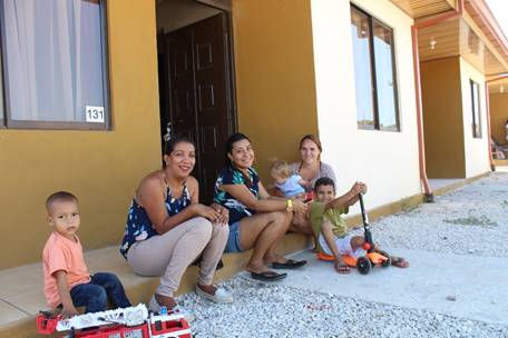 Familia beneficiada con el bono, sentados frente a la fachada 